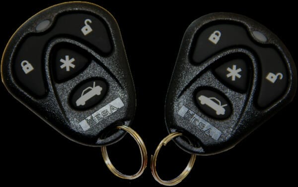 a man in a black jacket and jeans, wearing black gloves trying to break into a gray sedan with a screwdriver as part of our custom car alarm installation.